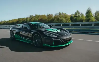 Czarny Rimac Nevera z zielonymi akcentami pędzi po torze, demonstrując swoją moc w przyspieszeniu 0-100 km/h.