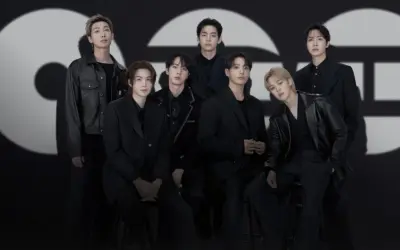 Die Mitglieder von BTS posieren in schicken schwarzen Outfits vor einem großen, stilisierten "GQ"-Logo.