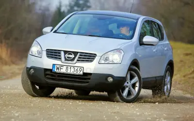 Srebrny Nissan Qashqai 2.0 benzyna na drodze szutrowej, kierowca za kierownicą.