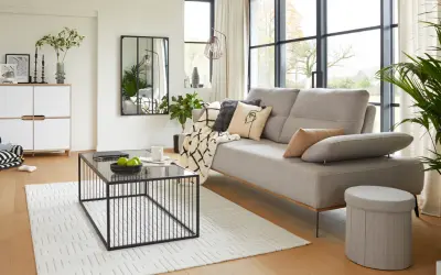 Salon moderne au style épuré avec canapé gris, table basse noire et meuble blanc.
