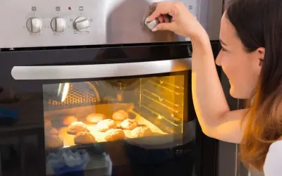 Kobieta ustawia temperaturę piekarnika, zastanawiając się, ile prądu zużywa piekarnik podczas pieczenia ciasteczek.