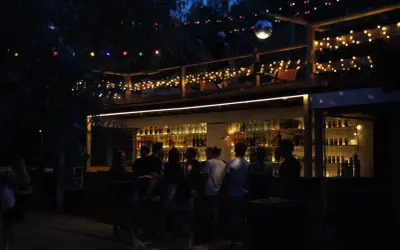 Nocna imprezowa ulica w Warszawie. Bar z kolorowymi światłami i ludźmi cieszącymi się wieczorem.