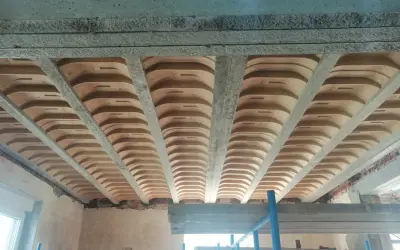 Widok od dołu na strop żelbetowy z pustakami ceramicznymi, tworzący charakterystyczny falisty wzór.