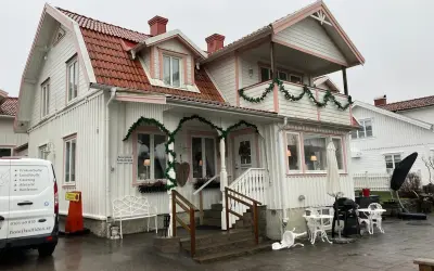 Vitt hus med rosa detaljer och juldekorationer. Skylt visar "Reception Restaurang". Kanske en titt på restaurang Solliden meny?
