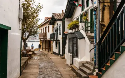 Calle empedrada con casas blancas y balcones de madera, ideal para pasear y descubrir qué ver en Algorta.