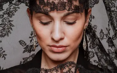 Mujer con peinados de mantilla, luciendo pendientes largos y un abanico de encaje.