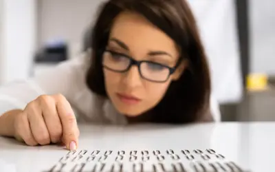 Kobieta w okularach z uwagą układa spinacze, co może sugerować kompulsywne zachowania.