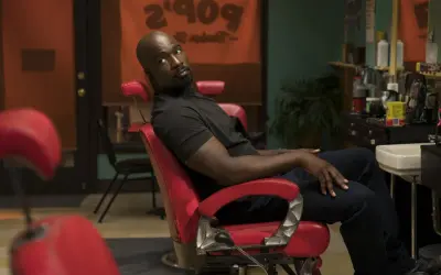 Luke Cage obsada: Mike Colter w czerwonym fotelu fryzjerskim, w tle szyld "Pop's Barber Shop".