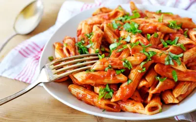 Penne w pikantnym sosie pomidorowym, posypane świeżą bazylią. Idealne spaghetti arrabiata na obiad.