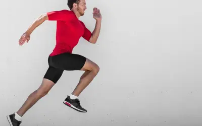 Ein Mann in rotem Shirt und schwarzen Shorts läuft mit hoher Kadenz gegen eine Betonwand.