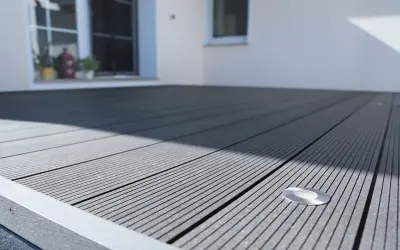 Moderne Terrasse mit grauen WPC Terrassendielen verlegen. Ein kleiner Bodenspot ist bereits integriert.