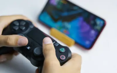 Ręce trzymające kontroler DualSense, gotowe do gry na telefonie. Dowiedz się, jak podłączyć pada PS5 do telefonu, by cieszyć się grami mobilnymi na nowym poziomie.