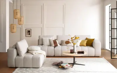 Gemütliches Wohnzimmer mit beiger Couch, Korb-Lampen und einem runden Tisch. Perfekt für slow living einrichtung.