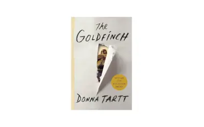 Okładka książki "Szczygieł" Donny Tartt, z wyłaniającym się spod podartego papieru ptakiem i żółtym okręgiem z napisem "WINNER OF THE PULITZER PRIZE".