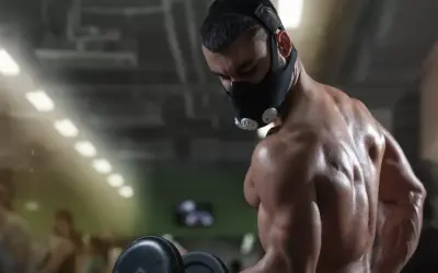 A muscular man trains with an oxygen restriction mask, exploring the oxygen restriction mask benefits for enhanced performance.