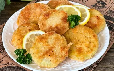 Knusprige Kohlrabi-Schnitzel auf einem Teller mit Zitronenscheiben und Petersilie garniert. Ein köstliches vegetarisches Gericht.