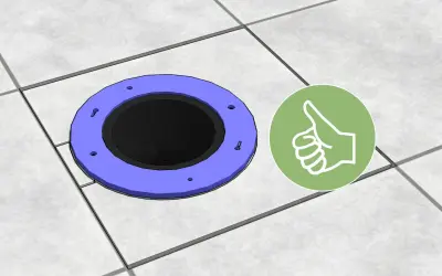 A toilet flange sits on tiled flooring, showing how to cut tile around toilet for a perfect fit. A green thumbs-up icon indicates success.