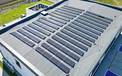 Duży płaski dach pokryty panelami fotowoltaicznymi, które zbierają energię słoneczną.