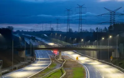 Nowa obwodnica Żukowa nocą, oświetlona latarniami, z linią wysokiego napięcia w tle.