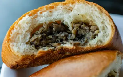 Puszysta bułka z pieczarkami, przekrojona na pół, odsłaniająca aromatyczne, drobno posiekane grzyby. Idealna na szybką przekąskę.