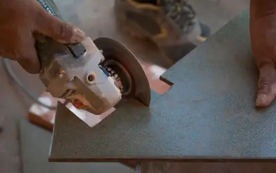 Mano sujetando una radial para cortar azulejos con precisión.