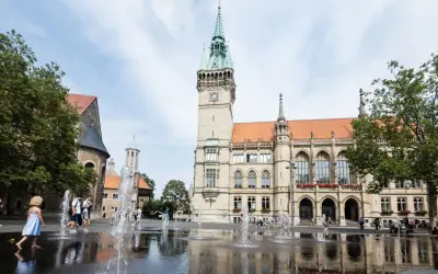 Kinder planschen im Brunnen vor dem Rathaus. Hier kann man in Braunschweig viel erleben, z.B. den Dom besichtigen.