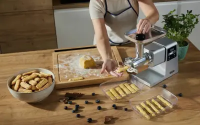 Przygotowywanie kruche ciasteczka do długiego przechowywania. Maszyna do ciastek formuje paski ciasta, które trafiają do pojemników.