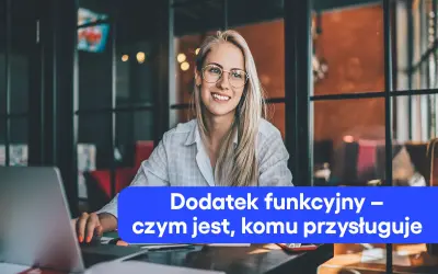 Uśmiechnięta blondynka w okularach pracuje przy laptopie. Na ekranie widnieje napis "Dodatek funkcyjny – czym jest, komu przysługuje".