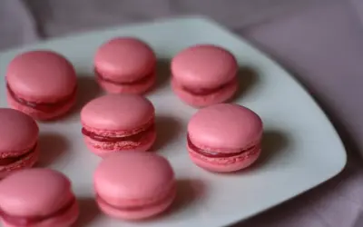 Rosa macarons med fyllning på en vit tallrik. Perfekt för ett macarons recept.