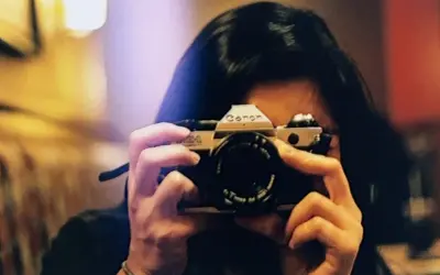 A person holds a Canon AE-1, a classic camera, ready to capture a moment. This camera is the best film for Canon AE-1 enthusiasts.