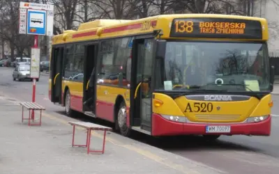 Żółto-czerwony autobus 138 warszawa z otwartymi drzwiami na przystanku.