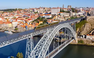 Most zwodzony w Porto z żółtym tramwajem, widok na miasto i rzekę. Szukasz informacji o wino porto cena?