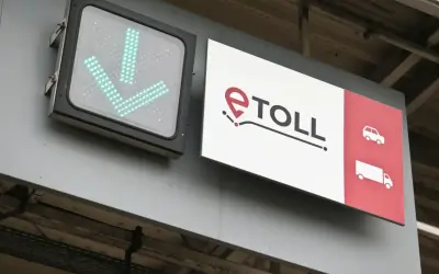 Znak e-TOLL z zielonymi strzałkami w dół i ikonami pojazdów.