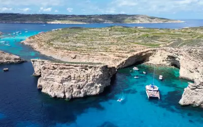 Malta co zobaczyć: Błękitna Laguna na Comino, z łodziami i klifami, to idealne miejsce na wakacje.
