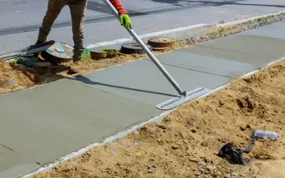 Robotnik wygładza świeży beton C25/30 na budowie chodnika.