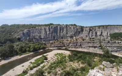 Un cirque de gens, des kayakistes profitent de la rivière au pied d'une falaise imposante.