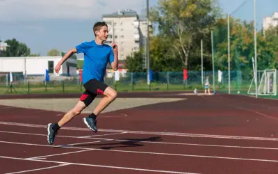 Młody biegacz na bieżni podczas zajęć sportowych dla młodzieży.