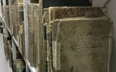 Des registres anciens, certains marqués "archive 07", s'alignent sur des étagères métalliques, témoins silencieux du temps.
