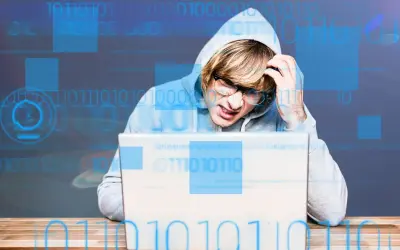 Młody mężczyzna w kapturze zmagający się z problemem, zastanawia się, adware co to jest. Cyfrowy kod otacza go.