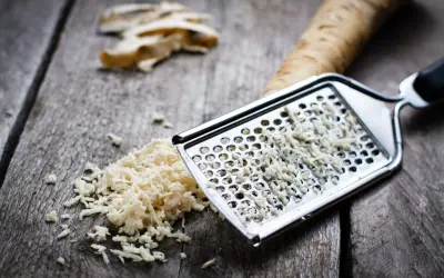 Tarty chrzan na desce, obok korzeń. Poznaj sekret, jak zetrzeć chrzan żeby nie płakać.