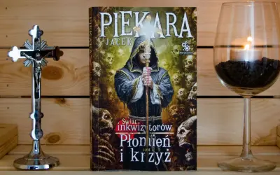 Książka "Świat inkwizytorów: Płonien i krzyż" obok krucyfiksu i świecy. Jacek Piekara opowiada o kolejności działań inkwizytora.