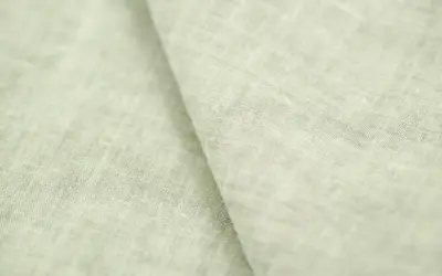 Miękki, jasnozielony len materiał z widoczną fakturą splotu.