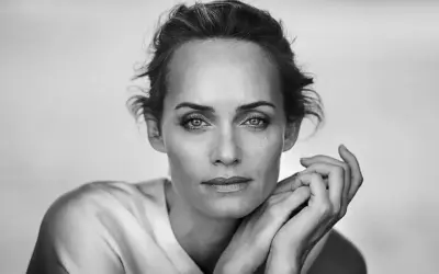 Ritratto in bianco e nero di una donna con mani appoggiate al viso, un'espressione intensa catturata da un fotografo ritrattista famoso.