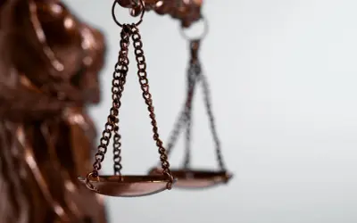 Waga sprawiedliwości, symbol równowagi. Obok niej widać fragment posągu Temidy, symbolizującej prawo. To metafora dla jednostki organizacyjnej nieposiadającej osobowości prawnej, która działa w ramach prawa.