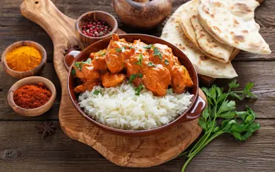 Pyszne chicken tikka masala z ryżem, podane z chlebkiem naan i przyprawami.