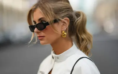 Mujer con coleta y gafas de sol, luciendo un corte de pelo con flequillo cortina que enmarca su rostro.