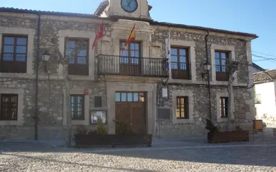 Ayuntamiento de Lozoyuela, con su fachada de piedra, balcón y reloj. Un lugar con mucho que ver.