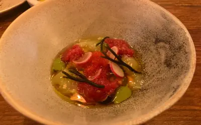 Un plato de mariscos con tomate picado, rábano y algas, servido en una **taberna oeste**.