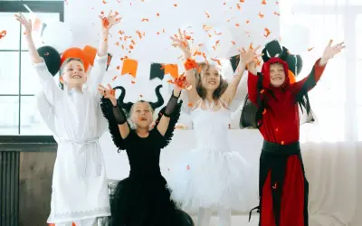 Dzieci w strojach aniołów i diabła rzucają konfetti.