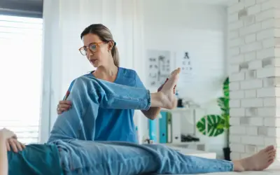 Fizjoterapeutka bada nogę pacjenta. Czy do fizjoterapeuty potrzebne jest skierowanie? Zależy od placówki.